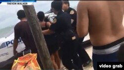 Policías de Miami detienen a algunos de los 15 cubanos ilegales que fueron capturados tras llegar a Virginia Key, de un grupo de 27.