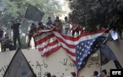 Manifestantes arrancan la bandera de la Embajada de Estados Unidos en El Cairo.