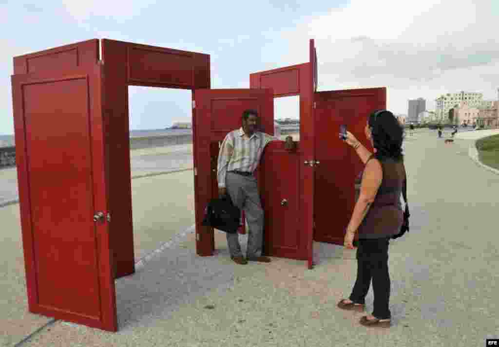 En la Bienal de La Habana un hombre es retratado junto a la obra Possible chances, del artista cubano Rafael Dom&egrave;nech, colocada en el malec&oacute;n de La Habana, Cuba.