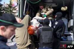 Soldados rescatan a una mujer herida entre las ruinas del bombardeo a la estación de trenes de Kramatorsk, Ucrania