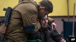 Un soldado consuela a Larysa Kolesnyk, de 82 años, luego de que fuera evacuada de Irpín, en las afueras de Kiev, Ucrania. 