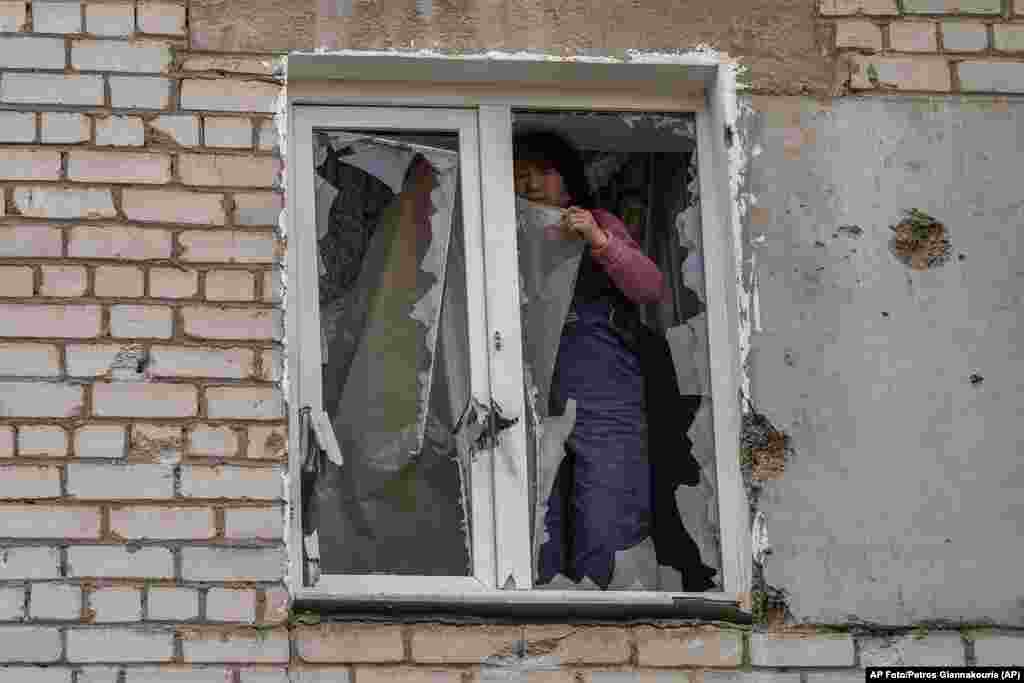 Una mujer coloca un plástico sobre su ventana dañada el martes 29 de marzo de 2022 tras un ataque ruso la noche anterior, en la zona residencial de Mykolaiv, Ucrania. (AP Foto/Petros Giannakouris)