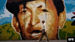 Un hombre camina junto a un mural del presidente venezolano, Hugo Chávez, en una calle de Caracas.