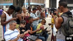 Un hombre (c) ofrece servicios de instalación de aplicaciones y softwares este 26 de septiembre de 2015, en La Habana (Cuba). Desde hace tres meses Cuba vive un inédito, aunque todavía limitado, incremento del acceso a internet con 35 nuevos puntos de con
