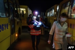 Un asistente de la Cruz Roja lleva a una chica del convoy de 30 buses con evacuados de Mariupol a Melitopol.