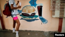 Una joven frente a la tablilla de precios en una cafetería en Guantánamo, Cuba. 