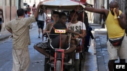 Varias personas esperan junto a una bicitaxi. 