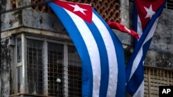 Banderas cubanas colgadas por los oficialistas cubren las ventanas de la casa de Yunior García, e impiden que se comunique con el exterior. (AP/Ramón Espinosa)