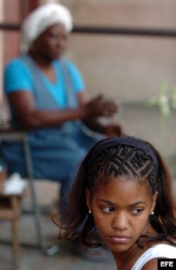 Una joven con un peinado afro permanece en el portal de su casa en Santiago de Cuba.