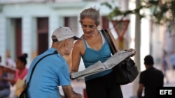 Dos personas leen el diario oficial Granma, en una calle de La Habana.