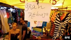 Detalle de un letrero que anuncia rebajas en una tienda de ropa importada ofertada por comerciantes privados.