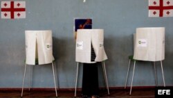 Una mujer prepara una cabina en un colegio electoral en Sartichala, a unos 30 kilómetros de Tbilisi, Georgia. 