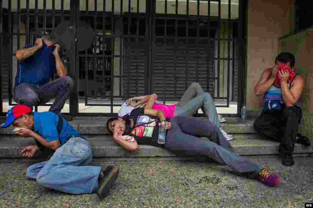 Un grupo manifestantes cubre sus rostros luego de recibir gases lacrimógenos lanzados por miembros de la Policía Nacional Bolivariana (PNB) durante una protesta, miércoles 18 de mayo de 2016.