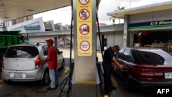 Un empleado y un cliente bombean combustible en una gasolinera de Caracas, en julio de 2018. El presidente Nicolás Maduro quiere regular el precio del combustible para la gasolina más barata del mundo, a través del "Carnet de la Patria" -un documento electrónico para disribuir subsidios a sus simpatizantes.