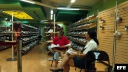 Dos empleadas leen el periódico en una tienda de calzado deportivo ubicada en el Centro Comercial Carlos III.