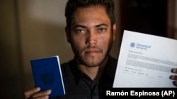 El cubano Marcos Marzo posa con su pasaporte y su permiso para viajar a Estados Unidos, en La Habana, el 25 de enero de 2023, tras recibir la aprobación a su solicitud de parole humanitario.