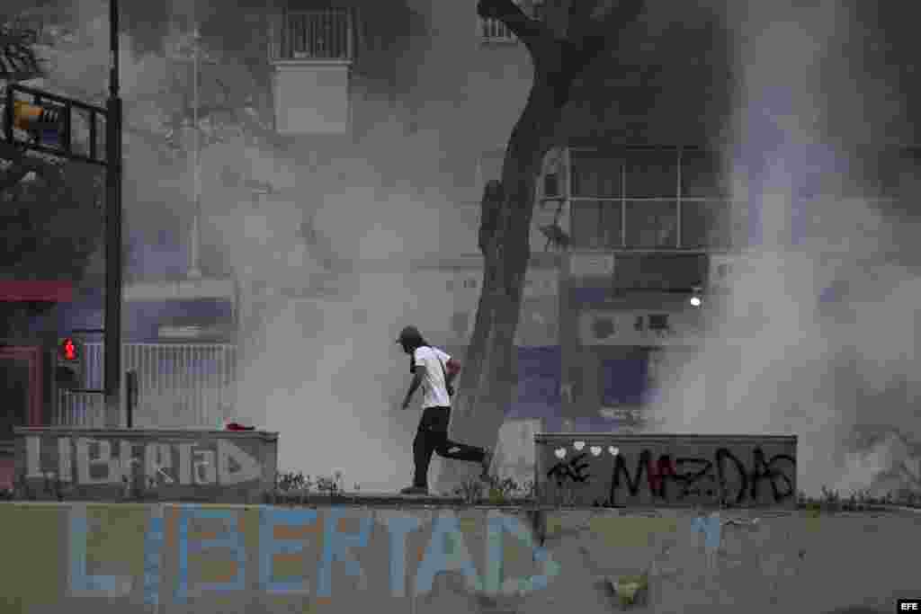 Un manifestante corre entre gases lanzados por integrantes de la Policía Nacional Bolivariana (PNB) durante una protesta contra el gobierno del presidente venezolano Nicolás Maduro.