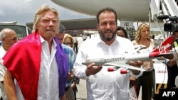 El entonces Ministro de Turismo Manuel Marrero sostiene un modelo a escala de un Boeing 747 de la aerolínea británica Virgin Atlantic, junto a su dueño, el magnate Richard Branson, en La Habana, en junio de 2005. (Luis Acosta/AFP)