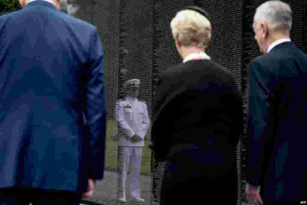 El teniente de Marina Jack McCain, hijo del fallecido Senador John McCain, se refleja en el muro que recoge los nombres de los caídos en Vietnam después que su madre, Cindy McCain, acompañada por el secretario de Defensa Jim Mattis (d) y el jefe de gabin