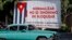Un auto pasa junto a un cartel alusivo al embargo estadounidense a Cuba.