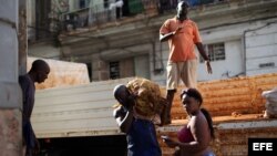 Varios obreros descargan un camión de papas en un mercado de La Habana.