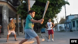 Niños cubanos en un improvisado juego callejero de béisbol.