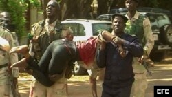 Personal militar de Mali traslada a una mujer herida a su salida del hotel de lujo Radisson Blu en Bamako. EFE