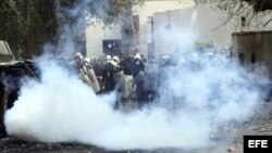  Agentes de policía antidisturbios egipcios, tratan de protegerse de los gases lacrimógenos lanzados por los manifestantes durante una protesta contra el "decretazo" del presidente egipcio, Mohamed Morsi. 