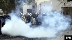  Agentes de policía antidisturbios egipcios, tratan de protegerse de los gases lacrimógenos lanzados por los manifestantes durante una protesta contra el "decretazo" del presidente egipcio, Mohamed Morsi. 