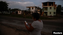 Una mujer usa su teléfono móvil durante un apagón, en Ciénaga de Zapata. Matanzas, el 7 de abril de 2026. 