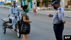 Un policía hace chequeos de peatones el sábado en el barrio El Carmelo, que el gobierno anunció inicialmente que iba a aislar y luego mantuvo abierto por temor a que se hiciera aún más difícil el acceso a provisiones, según reporta el diario 14ymedio (Foto: Yamil Lage/AFP).