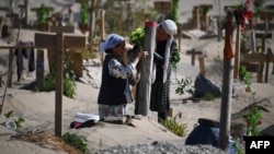 Mujeres uigures decoran una tumba en las afueras de Hotan, en la región de Xinjiang (Foto: AFP).