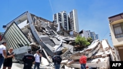 Varias personas permanecen cerca de un edificio derrumbado tras un terremoto en Manizales, Colombia, el 10 de agosto de 2026.