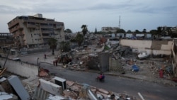 Personas en bicicleta pasan junto a edificios dañados tras los terremotos del 24 de junio, en La Guaira, Venezuela.