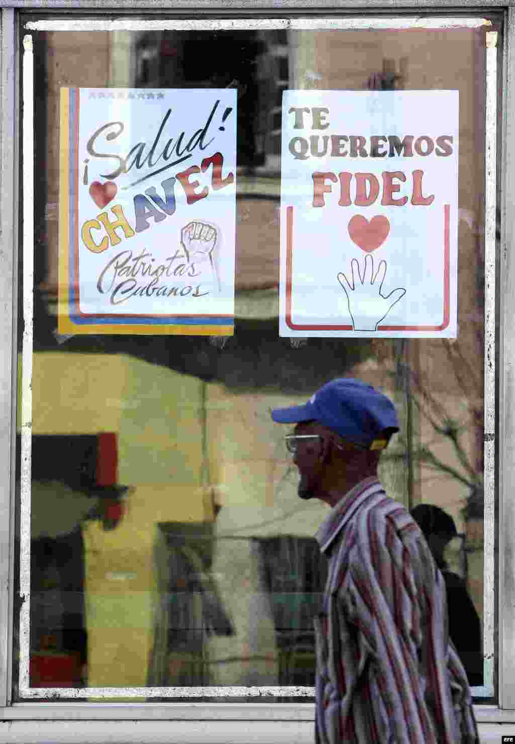 Un hombre camina junto a un cartel alusivo al presidente de Venezuela, Hugo Chávez