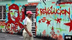 Un hombre pasa frente a un mural que tiene pintada la imagen de Ernesto "Che" Guevara.