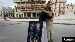 Familiares de una víctima de la explosión del Hotel Saratoga se abrazan durante una vigilia con velas en La Habana, el 22 de mayo de 2022. (REUTERS/Alexandre Meneghini).