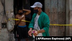 Un trabajador de la salud desinfecta sus manos en frente de una casa en cuarentena, en La Habana. ( AP/Ramon Espinosa)