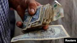 Un hombre sostiene un fajo de pesos cubanos y CUC. REUTERS/Desmond Boylan