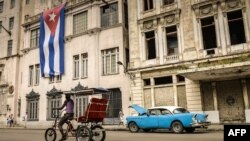 Un bicitaxi y un almendrón circulan por La Habana. (Archivo)