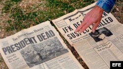 Un hombre muestra un periódico de 1963 que informa sobre el asesinato de Kennedy en el monumento en memoria de John F. Kennedy en Dealey Plaza, Dallas, Texas, EEUU.