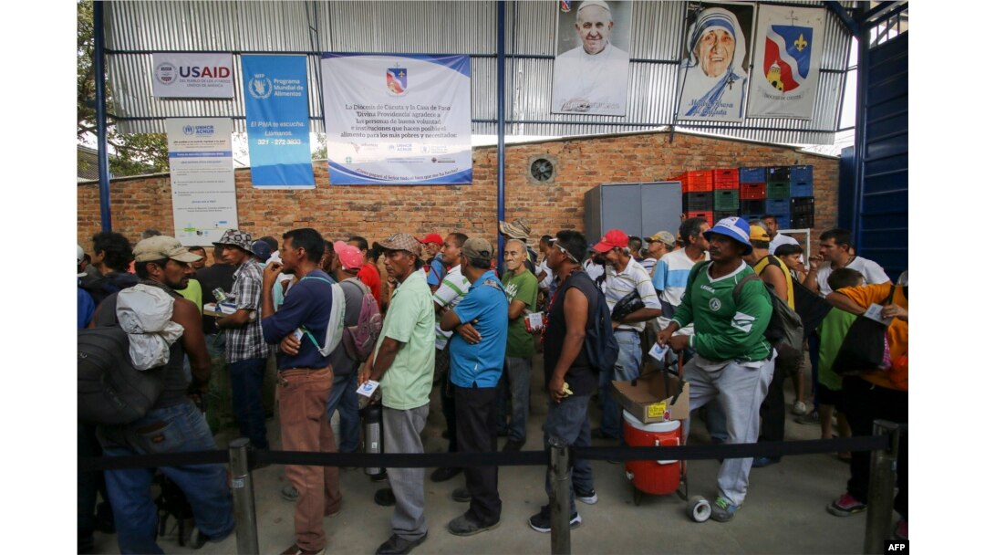 Una interminable fila de personas que esperan al sol durante horas para recibir un plato de comida.