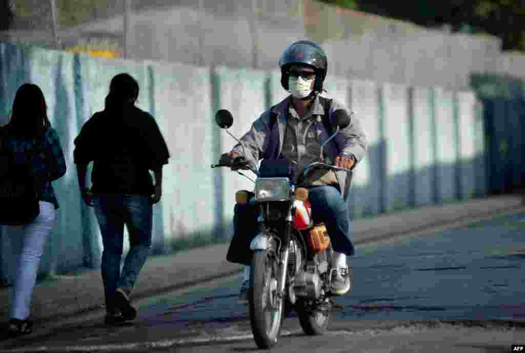  Un hombre usa una m&#225;scara facial mientras conduce una moto en La Habana.
