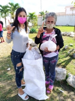 Roxana García Lorenzo, una de las promotoras de la iniciativa, entrega la ayuda a la familiar de tres de los detenidos.