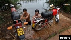 Un grupo de jóvenes lavan sus motocicleetas en el Río Guanímar.