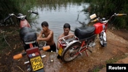 Young men wash their motorcycles in the Guanimar River.