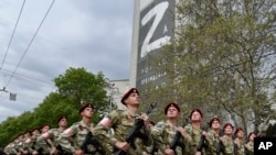 Soldados rusos marchan junto a un edificio al fondo se ve la imagen de la letra Z, que se ha convertido en un símbolo del ejército de Rusia, el jueves 5 de mayo de 2022, en Sebastopol, Crimea.