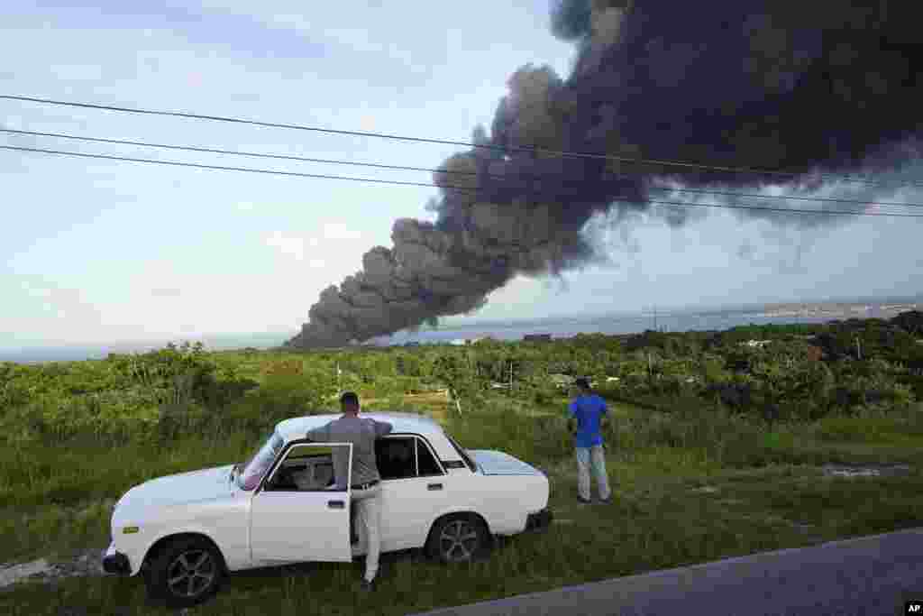 Residentes de zonas cercanas a la base de supertanqueros de Matanzas observan la columna de humo negro que se desprende del incendio. Cerca de 5 mil residentes han sido evacuados. (AP/Ramon Espinosa)