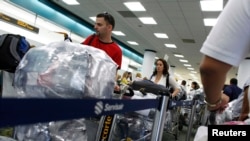 Cubanos cargados de equipaje hacen fila en el Aeropuerto Internacional de Miami para viajar a la isla. (REUTERS/Carlos Barria/Archivo).
