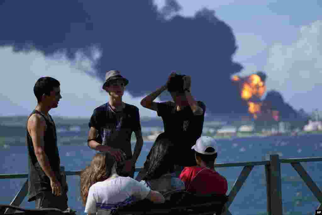 Jóvenes observan la columna de humo que se eleva del sitio de la catástrofe, en la zona industrial de Matanzas. Las autoridades advierten del peligro de contaminación. (AP/Ramon Espinosa)